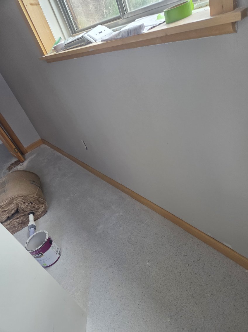 Freshly painted gray wall with natural wood trim and window by A1M Construction